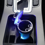 The LED ashtray sitting in a car centre console cup holder with the lid open and the light ring lit
