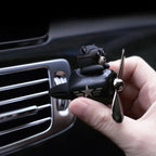 Hand clipping the aviator bear diffuser onto a car dashboard air vent