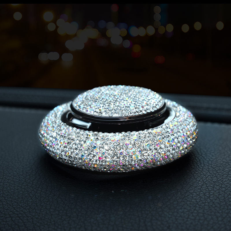 Crystal rhinestone car fragrance diffuser resting on a car dashboard at night