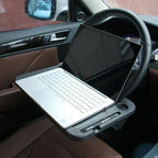 Laptop open on the desk tray clipped to a car steering wheel