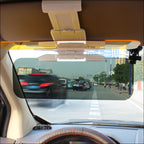 Anti-glare car sun visor flipped down behind the windscreen, cutting glare on a city street, seen from the driver's seat