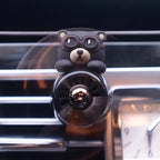 Car Vent Aromatherapy Set in use — black aviator bear clipped to a dashboard vent beside the dash clock