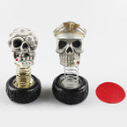Both skull dashboard ornaments side by side — the officer cap skull and the sunflower skull — on spring-mounted tyre bases