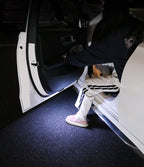 Door open warning light shining on the ground as a driver steps out of an open car door
