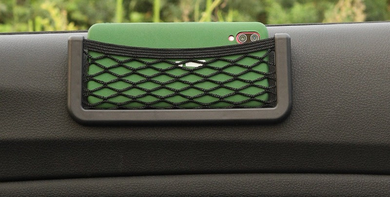 Stick-on mesh pocket on a car dashboard holding a phone