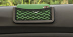 Stick-on mesh pocket on a car dashboard holding a phone