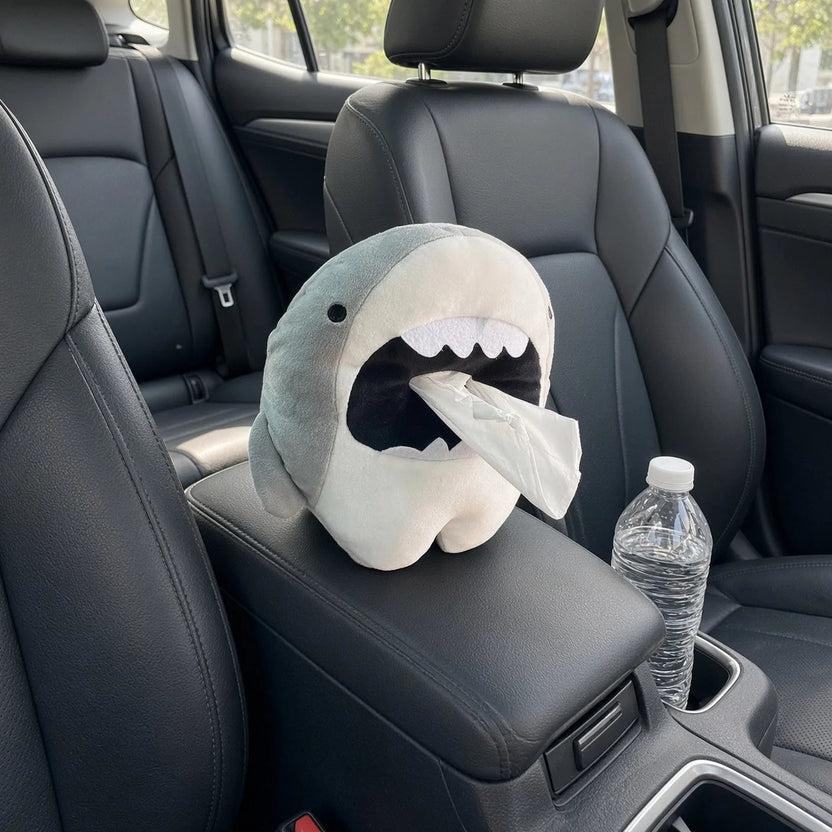 Shark car tissue box holder sitting on a centre console between the front seats, tissue pulled from the mouth