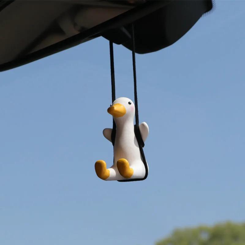 Car rearview mirror duck charm hanging from the rearview mirror against the windscreen